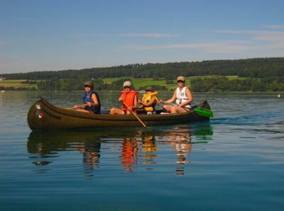Auf dem Hallwilersee bei Beinwil am See (5712, Kanton Aargau) paddelt eine Familie in einem Kanu über das ruhige Wasser unter blauem Himmel.Auf dem Hallwilersee bei Beinwil am See (5712, Kanton Aargau) paddelt eine Familie in einem Kanu über das ruhige Wasser unter blauem Himmel.