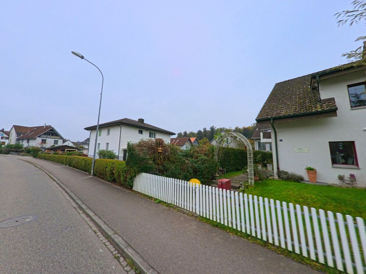 In einer Wohnsiedlung von Mülligen (5243, Kanton Aargau) säumen gepflegte Einfamilienhäuser mit Vorgärten und Hecken eine ruhige Strasse.
