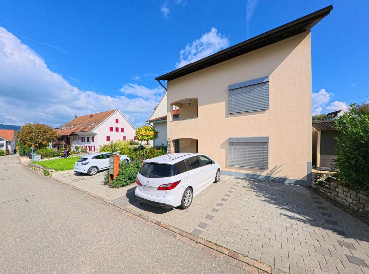 Mehrere Einfamilienhaeuser mit gepflegten Gaerten und geparkten Autos stehen in einer ruhigen Strasse von Münchwilen (4333, Kanton Aargau).