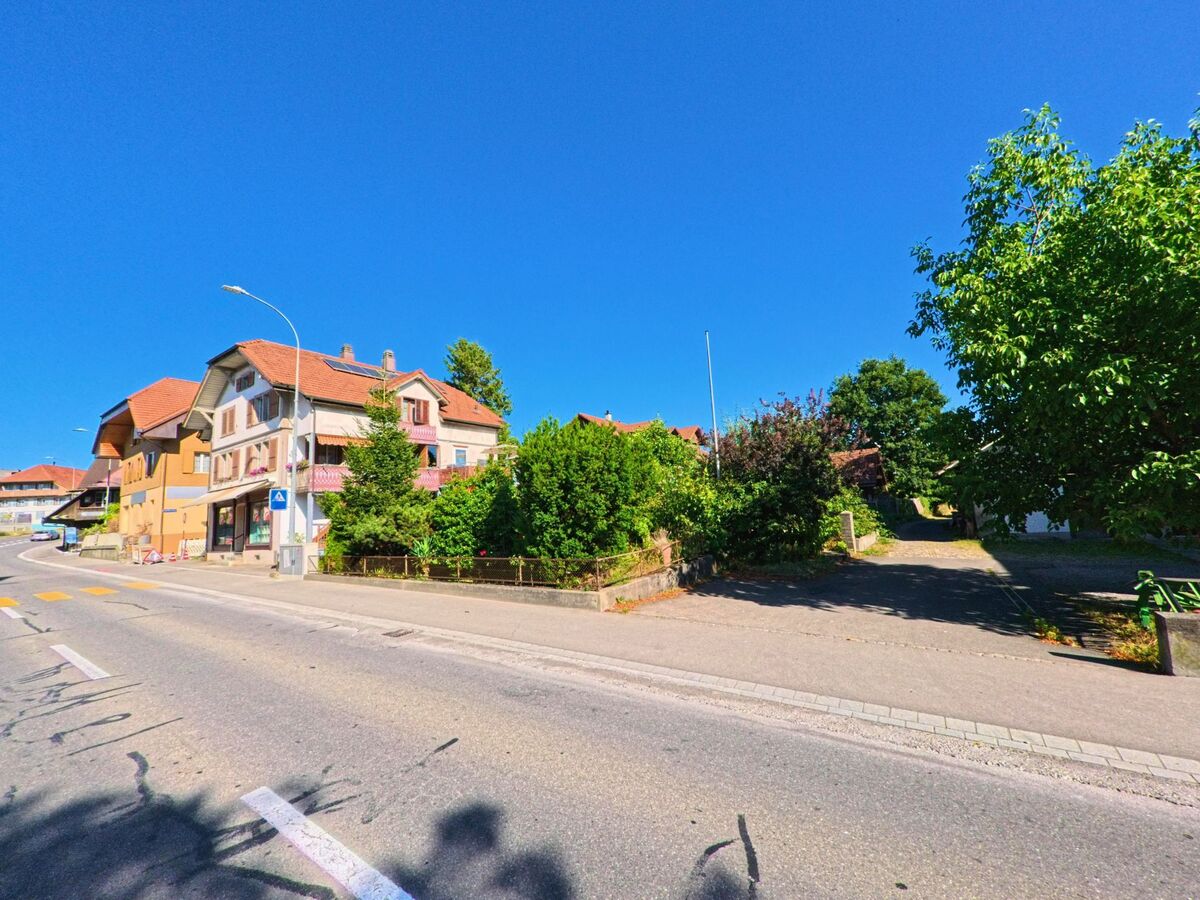 Entlang einer leicht ansteigenden Strasse in Münsingen (3110, Kanton Bern) stehen mehrstöckige Wohnhäuser mit Balkonen und gepflegten Vorgärten.