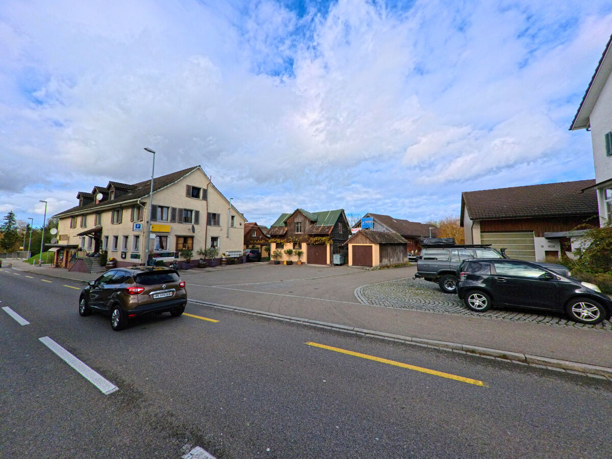 Mehrere Gebaeude gruppieren sich um einen offenen Platz im Dorfkern von Münsterlingen (8598, Kanton Thurgau).