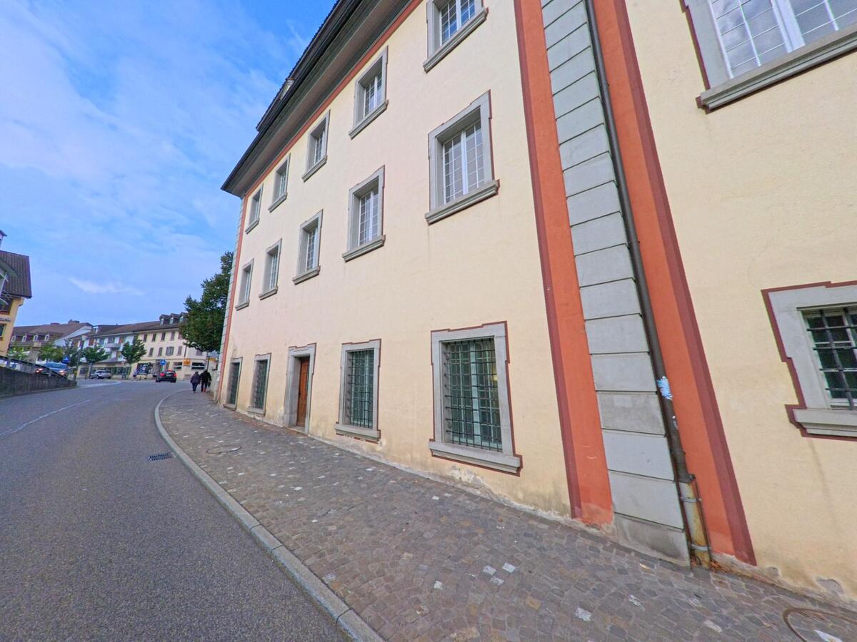 Eine gepflasterte Strasse mit historischen Gebaeuden fuehrt durch das Zentrum von Muri (5630, Kanton Aargau), wo Passanten entlang der Hausfassaden spazieren.