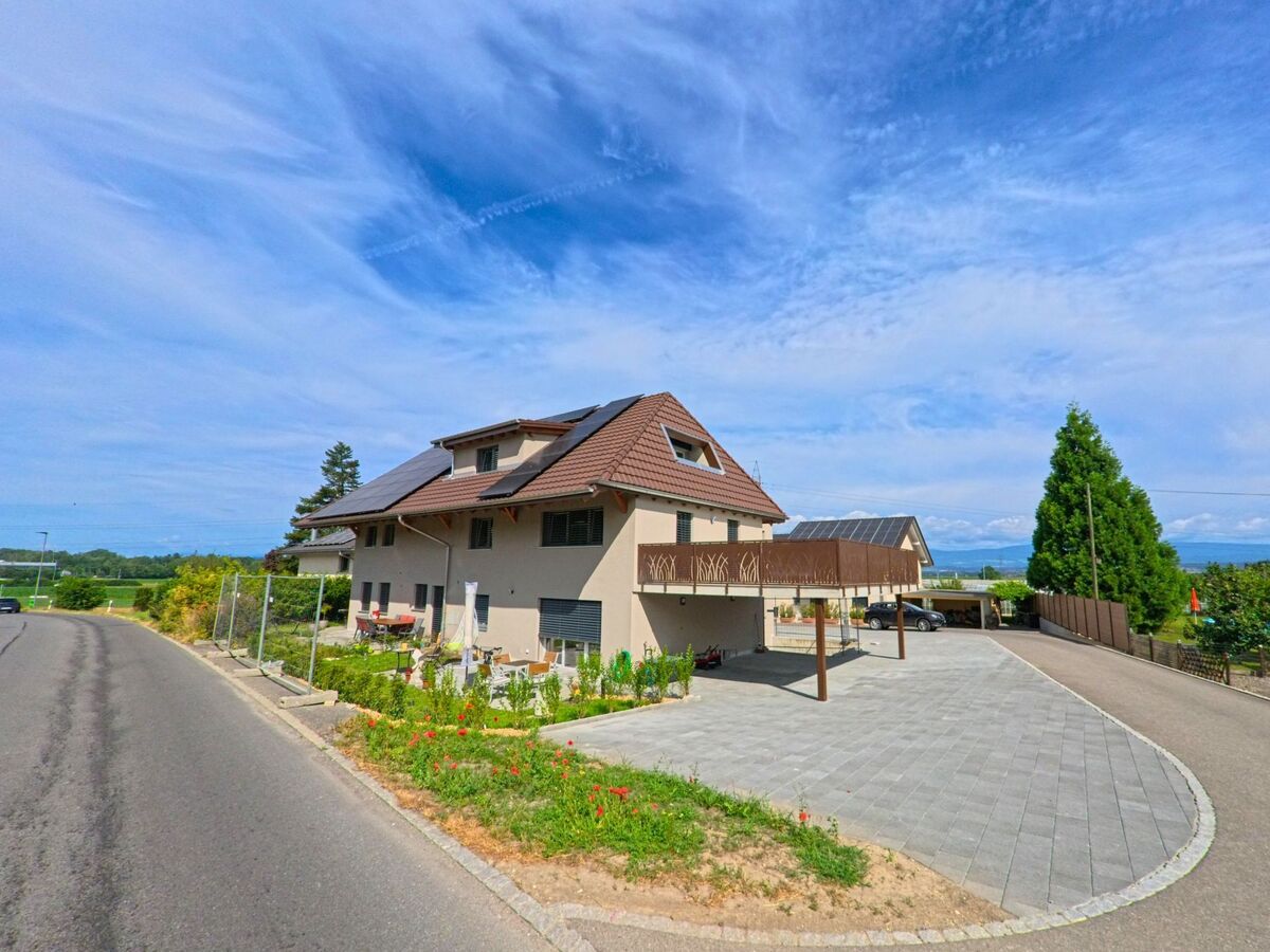 Ein modernes Wohnhaus mit Solarpanelen und grosszügigem Vorplatz liegt in Murten (3285, Kanton Freiburg) an einer ruhig verlaufenden Strasse mit Blick ins Grüne.