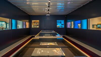 Im Musée Alexis Forel in Morges (1110, Kanton Waadt) werden kunstvolle Objekte und Miniaturen in beleuchteten Vitrinen entlang eines modernen Ausstellungsraums präsentiert.