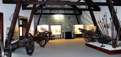 Im Musee d’Histoire in La Neuveville (2520, Kanton Bern) sind alte Kanonen, Helme und Waffen in einem Dachraum mit Holzbalken ausgestellt.