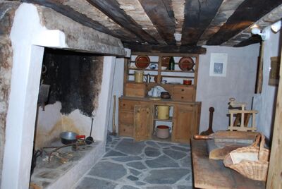 Im Musee Le Grand Lens in Lens (1978, Kanton Wallis) zeigt ein historischer Raum eine alte Kueche mit Kamin und Holzmoebeln.