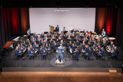 Auf der Bühne in Düdingen (3186, Kanton Freiburg) spielt die Musikgesellschaft als grosses Blasorchester unter der Leitung eines Dirigenten vor Publikum.