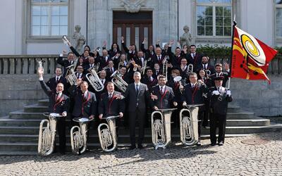 Mitglieder einer Musikgesellschaft stehen mit Instrumenten vor einem Gebaeude und jubeln gemeinsam in Haslen (9054, Kanton Appenzell Innerrhoden).
