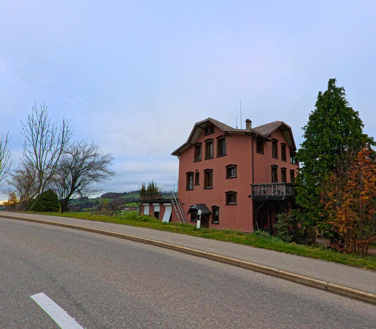 Ein rotes Wohnhaus liegt an der Hauptstrasse von Neckertal (9122, Kanton St. Gallen) mit freiem Blick ins Umfeld.