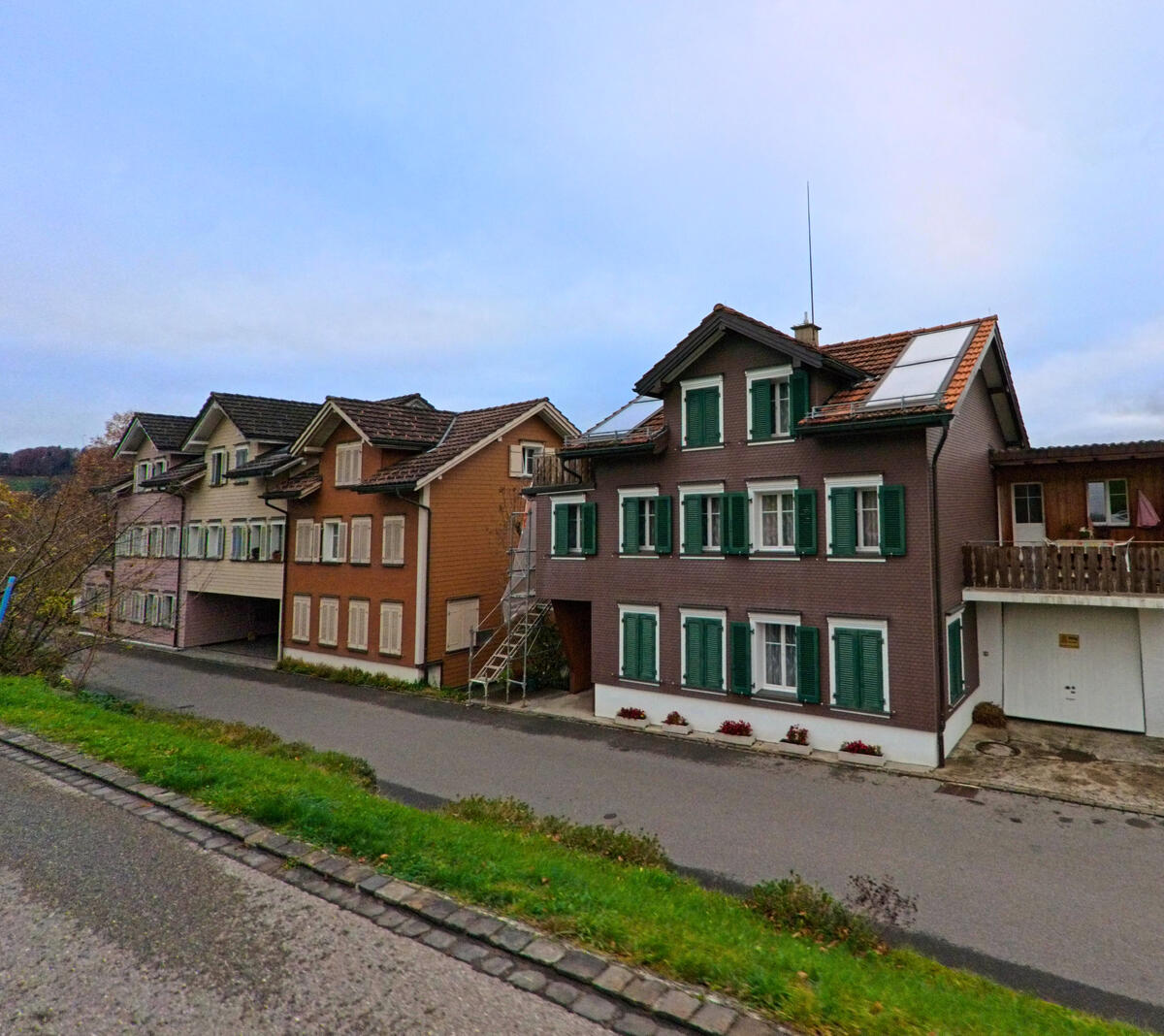 Mehrere Wohnhaeuser mit unterschiedlicher Fassadengestaltung reihen sich entlang der Strasse in Neckertal (9122, Kanton St. Gallen).