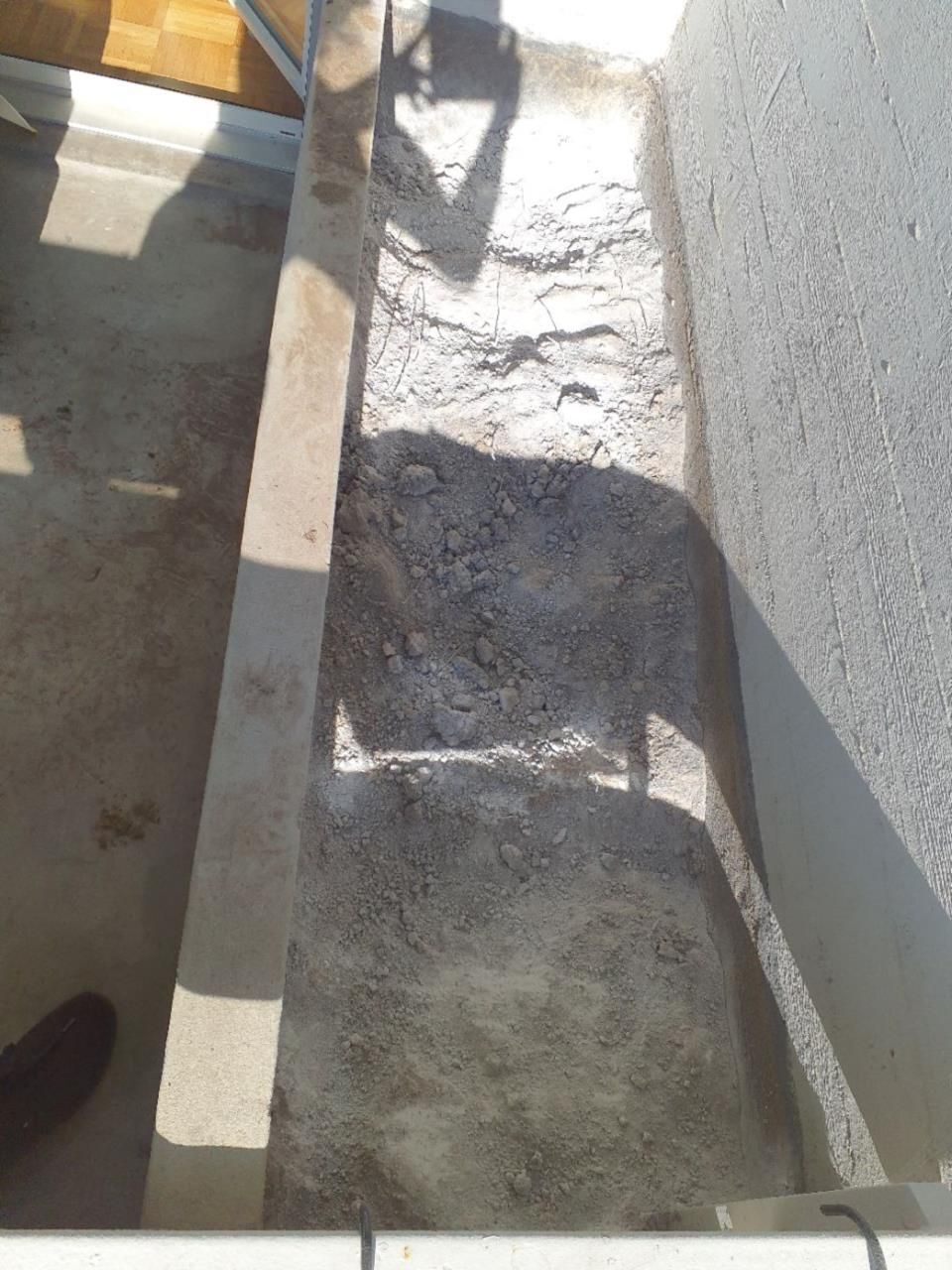 In Neftenbach (8413, Kanton Zürich) ist ein leerer, unebener Boden im Bereich eines Balkons zu sehen, auf dem eine Staubschicht liegt.
