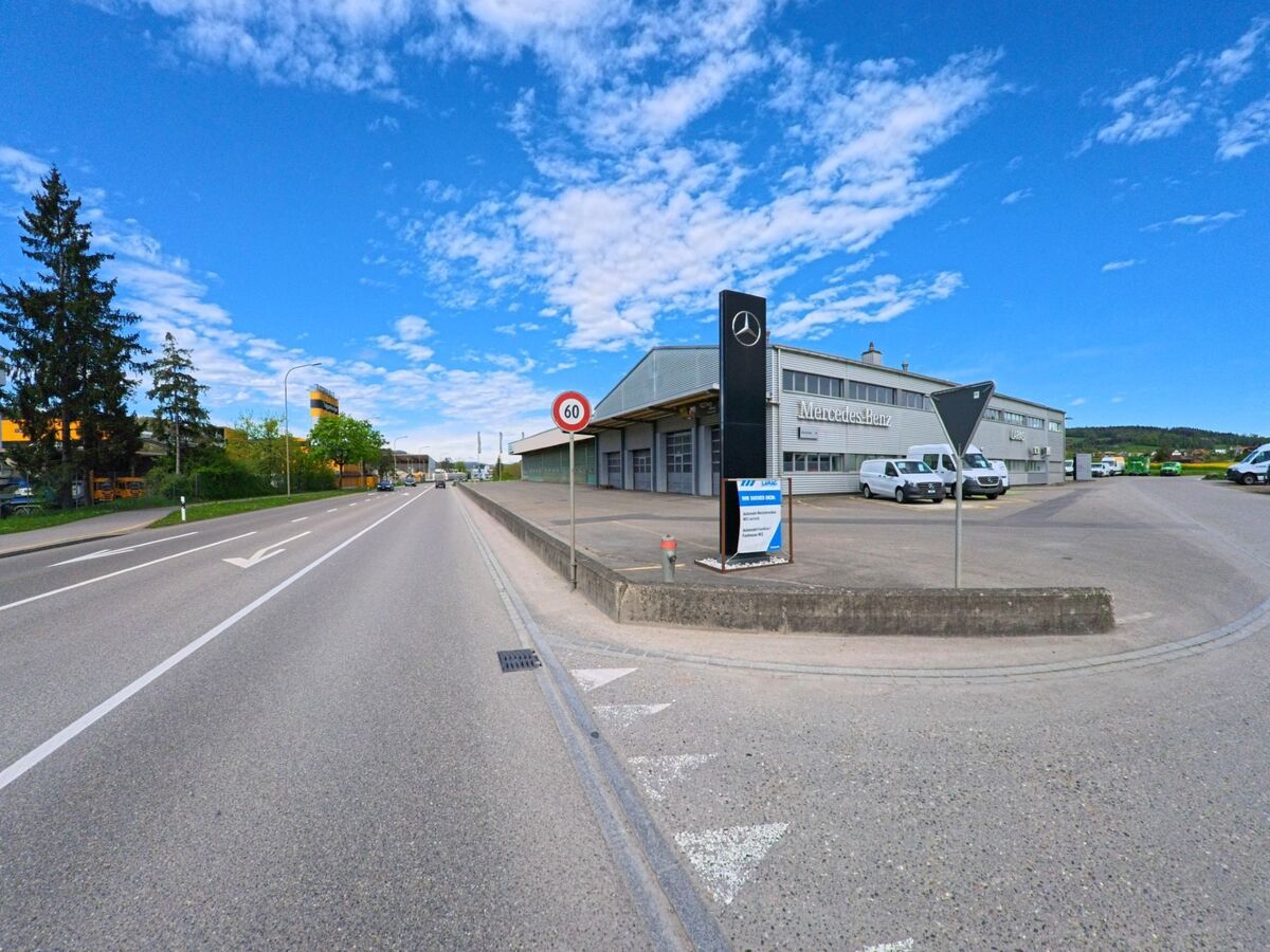  In Neftenbach (8413, Kanton Zürich) zeigt sich ein Mercedes-Benz Autohaus an der Hauptstrasse mit einem gut sichtbaren Geschwindigkeitsbegrenzungsschild.
