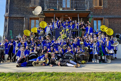 In Neuenkirch im Kanton Luzern posiert die Guggenmusik Neuechoebler Neuenkirch in blauen Kostuemen und mit ihren Instrumenten als grosse, farbenfrohe Gruppe vor einem Haus.