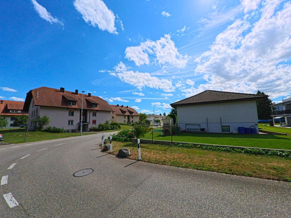 In einem Wohnquartier von Niederbuchsiten (4626, Kanton Solothurn) stehen Mehrfamilienhaeuser mit roten Dächern entlang einer ruhig verlaufenden Strasse.