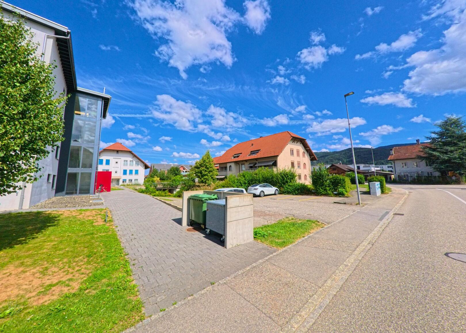 In Niederbuchsiten (4626, Kanton Solothurn) säumen moderne und traditionelle Wohnhäuser eine ruhige Seitenstrasse mit Blick auf den bewaldeten Jura.