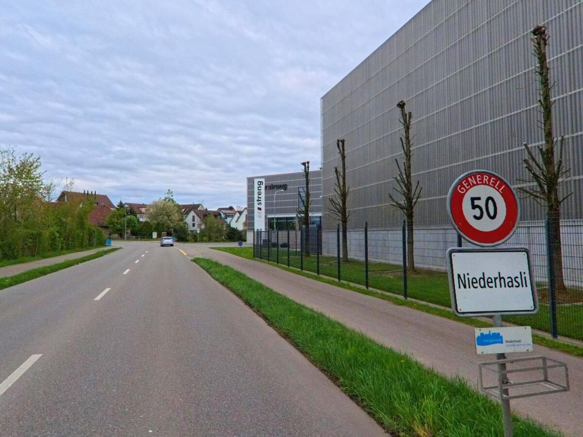 In Niederhasli im Kanton Zürich (PLZ 8155) markiert dieses Ortsschild mit Geschwindigkeitsbegrenzung den Übergang vom Industrieareal zur Wohnzone.