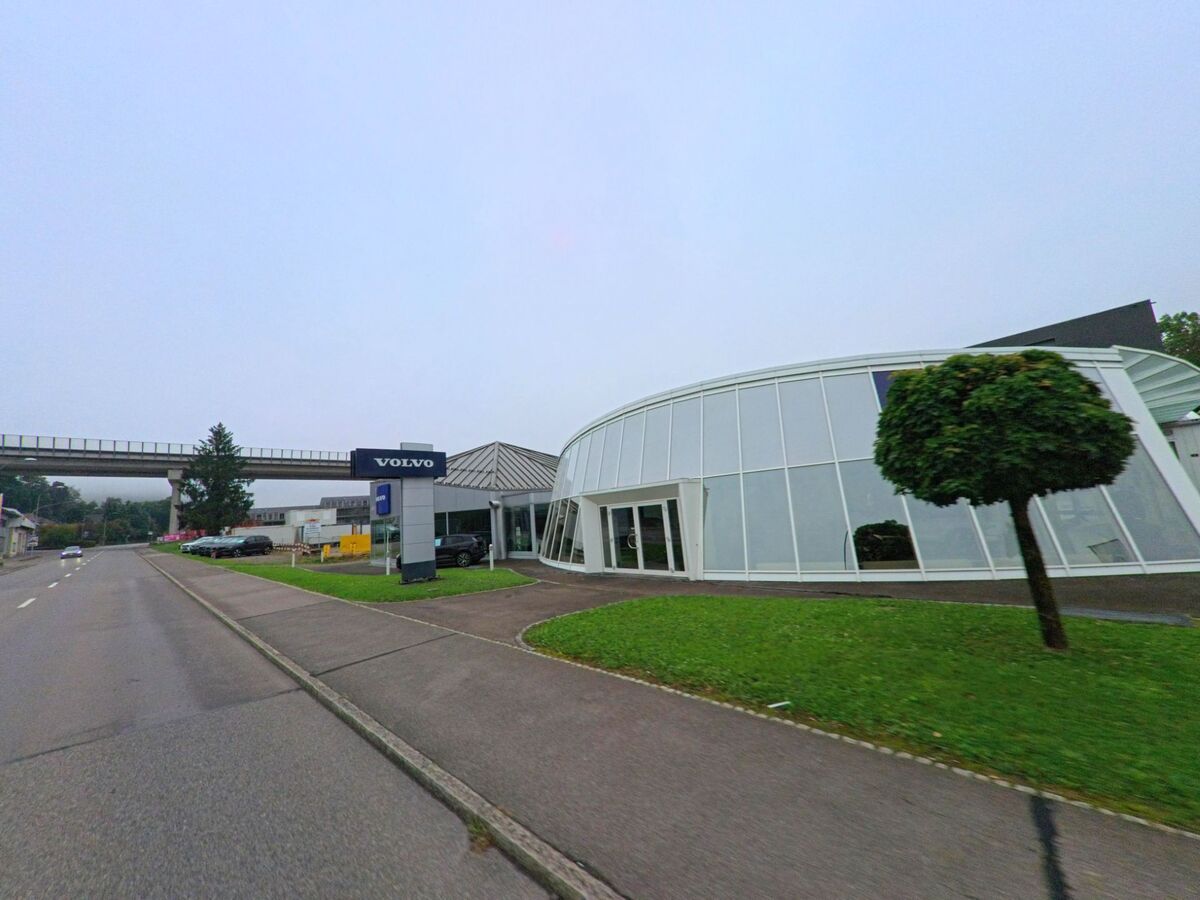 Am Ortsrand von Niederlenz (5702, Kanton Aargau) steht ein modernes Autohaus mit grosser Glasfassade und Volvo-Logo an der Strasse.