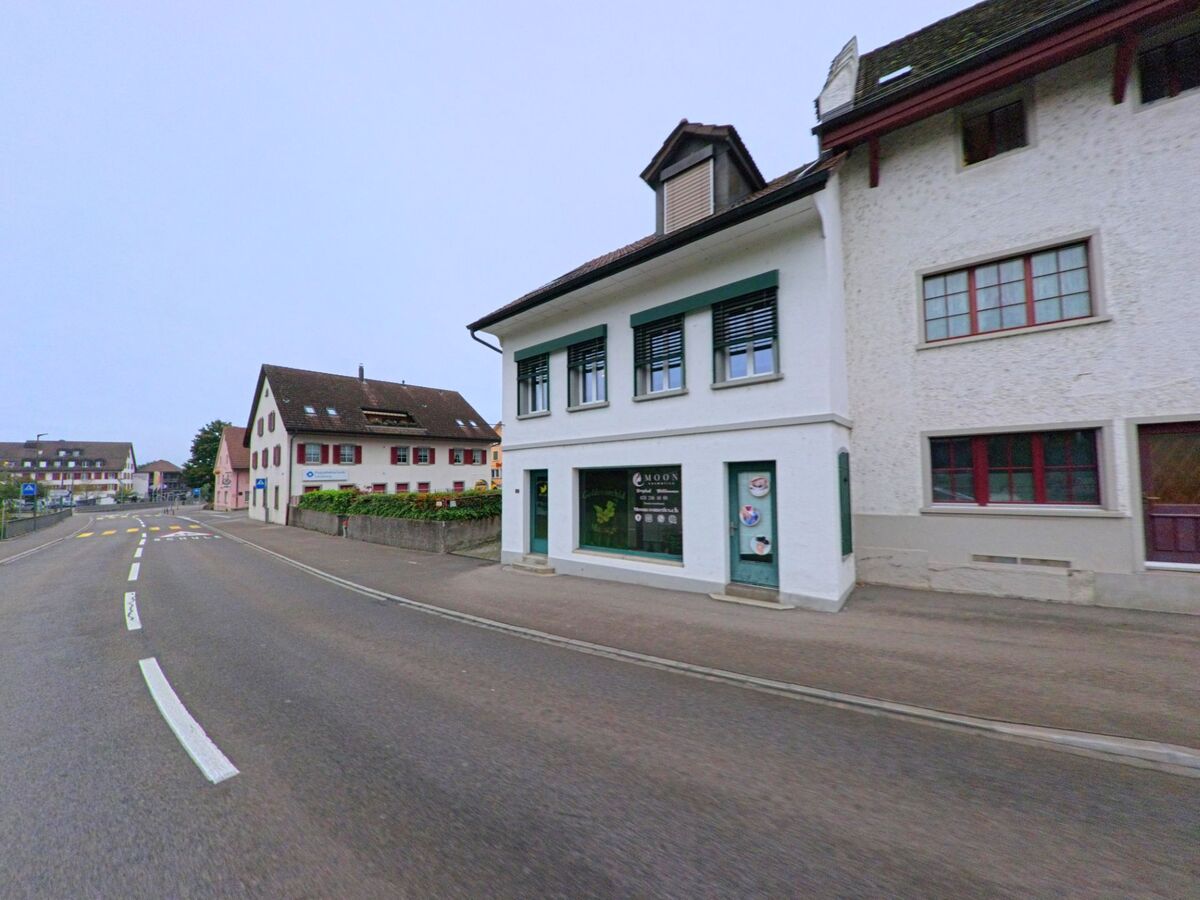 Entlang der Hauptstrasse in Niederlenz (5702, Kanton Aargau) stehen traditionelle Wohn- und Geschaeftshaeuser mit kleinen Laeden im Erdgeschoss.