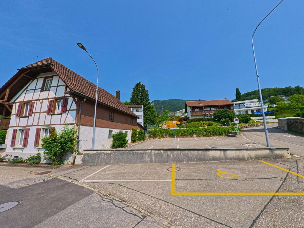 In Oberbipp (4538, Kanton Bern) steht ein traditionelles Fachwerkhaus an einem Parkplatz mit Behindertenparkplatz-Markierung nahe der Wolfsbergstrasse.