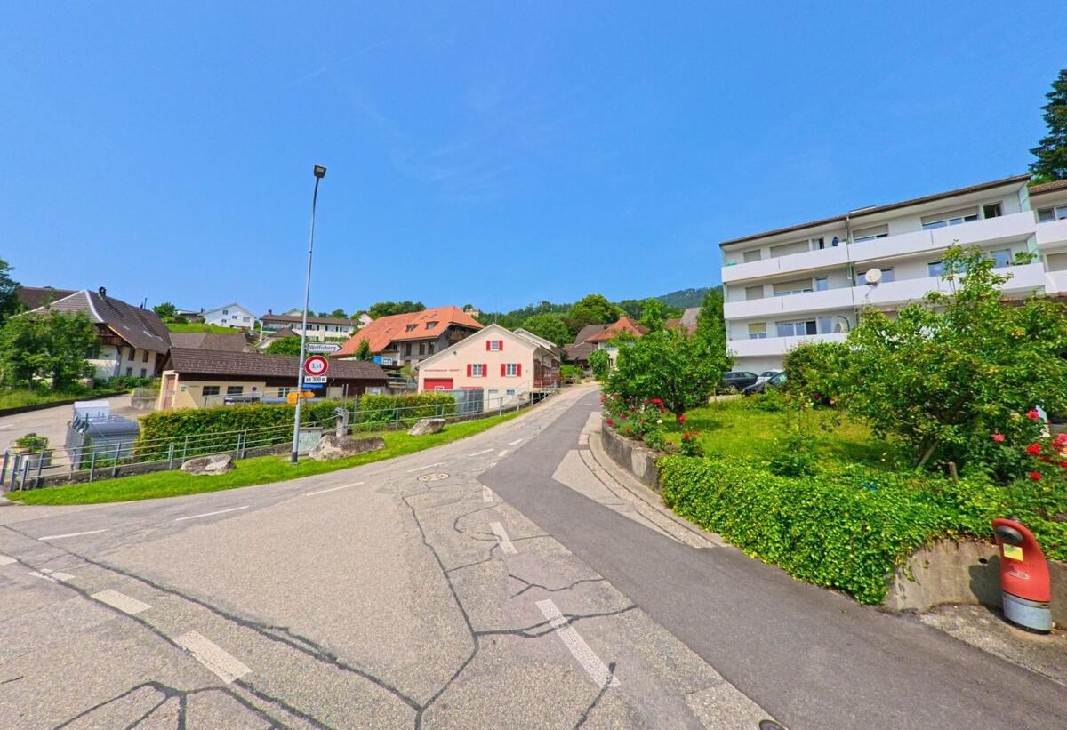 In Oberbipp (4538, Kanton Bern) führt die Wolfisbergstrasse vorbei an Mehrfamilienhäusern, Gärten und einem Bushaltestellenschild den Hang hinauf in ein ruhiges Wohnquartier.
