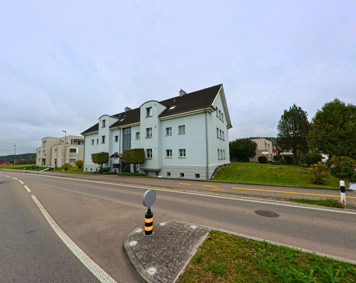 Mehrfamilienhaeuser mit Balkonen stehen an einer breiten Strasse in Oberbueren (9245, Kanton St. Gallen).