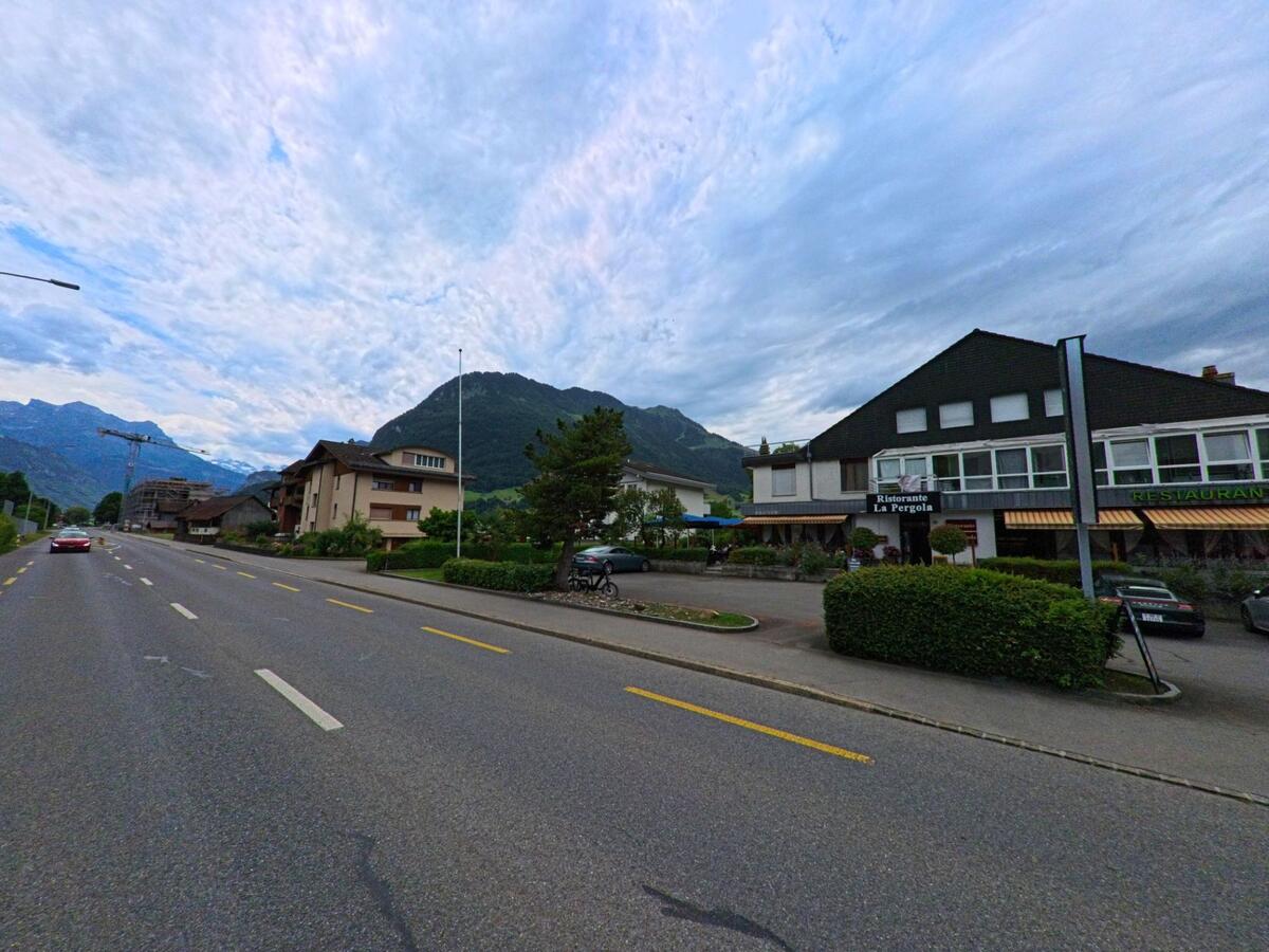 In Oberdorf (6370, Kanton Nidwalden) liegt das Restaurant La Pergola an einer breiten Durchgangsstrasse mit Blick auf bewaldete Berghaenge im Hintergrund.