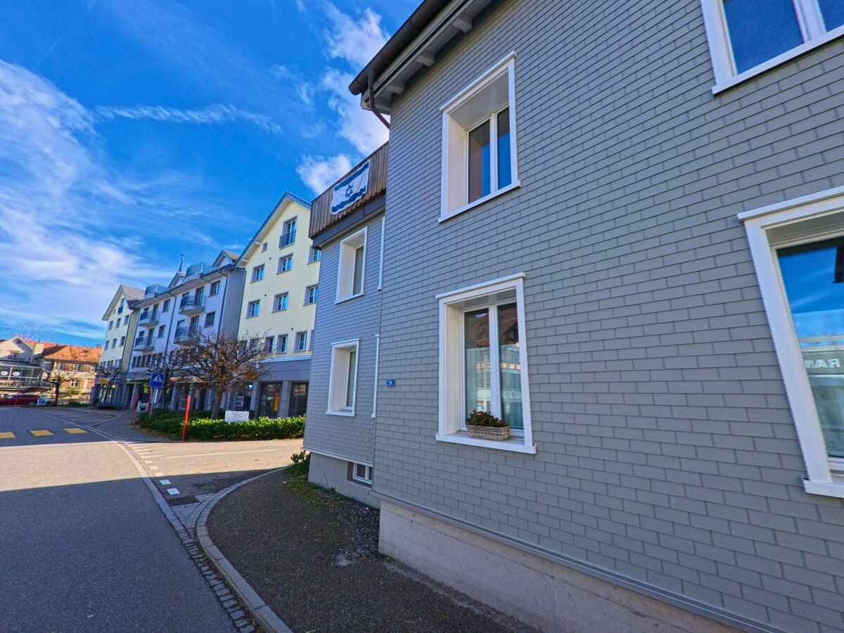 Ein modernes Wohngebäude mit schlichter Fassade steht am Rand einer Kurve in Oberegg (9413, Kanton Appenzell Innerrhoden).