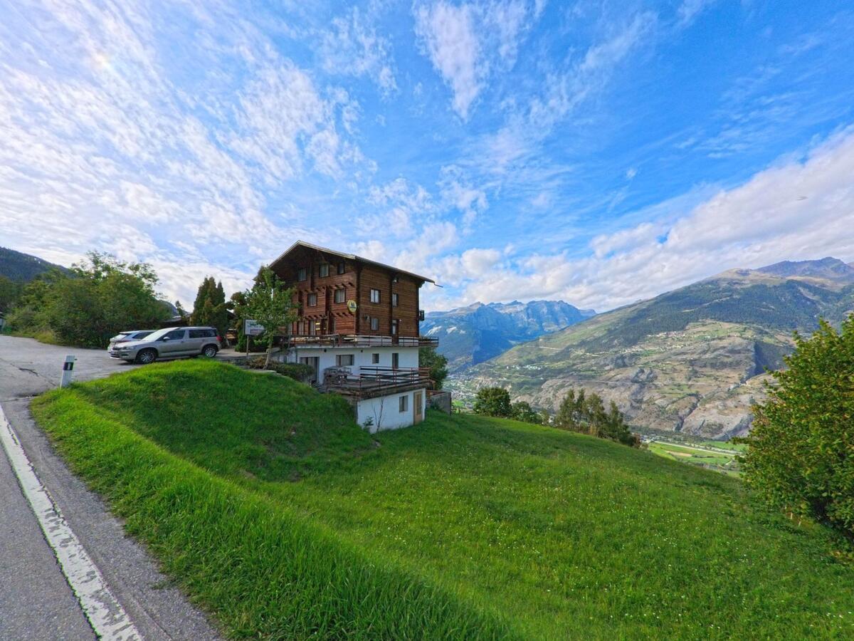 Ein traditionelles Holzhaus in Oberems (3948, Kanton Wallis) steht auf einer Anhöhe mit weitem Blick über das Tal und die Berge.