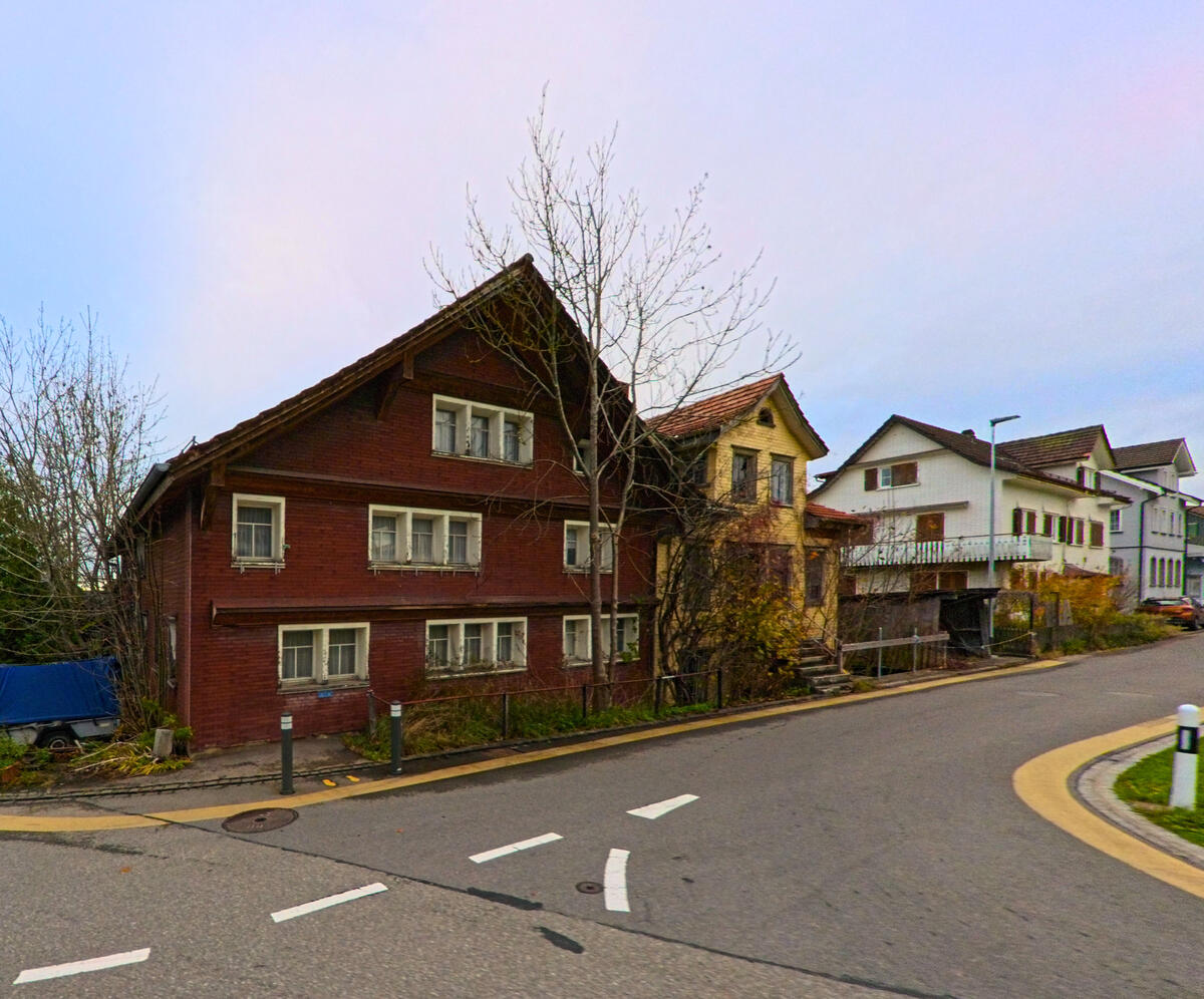 Traditionelle Wohnhaeuser mit Holzfassaden stehen an einer Kurve in Oberhelfenschwil (9125, Kanton St. Gallen).