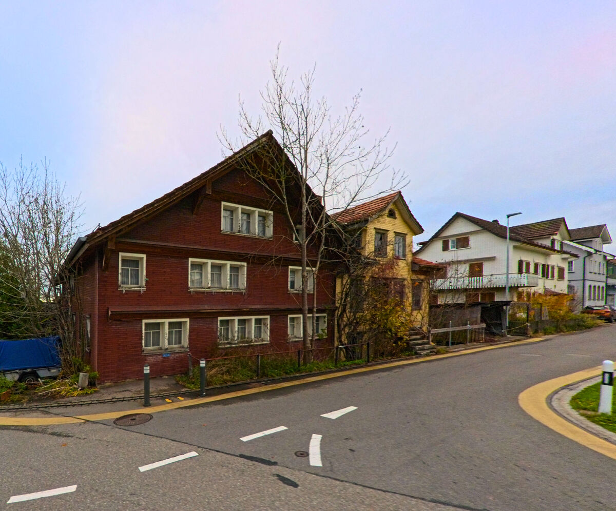 Traditionelle Wohnhaeuser mit Holzfassaden stehen an einer Kurve in Oberhelfenschwil (9125, Kanton St. Gallen).