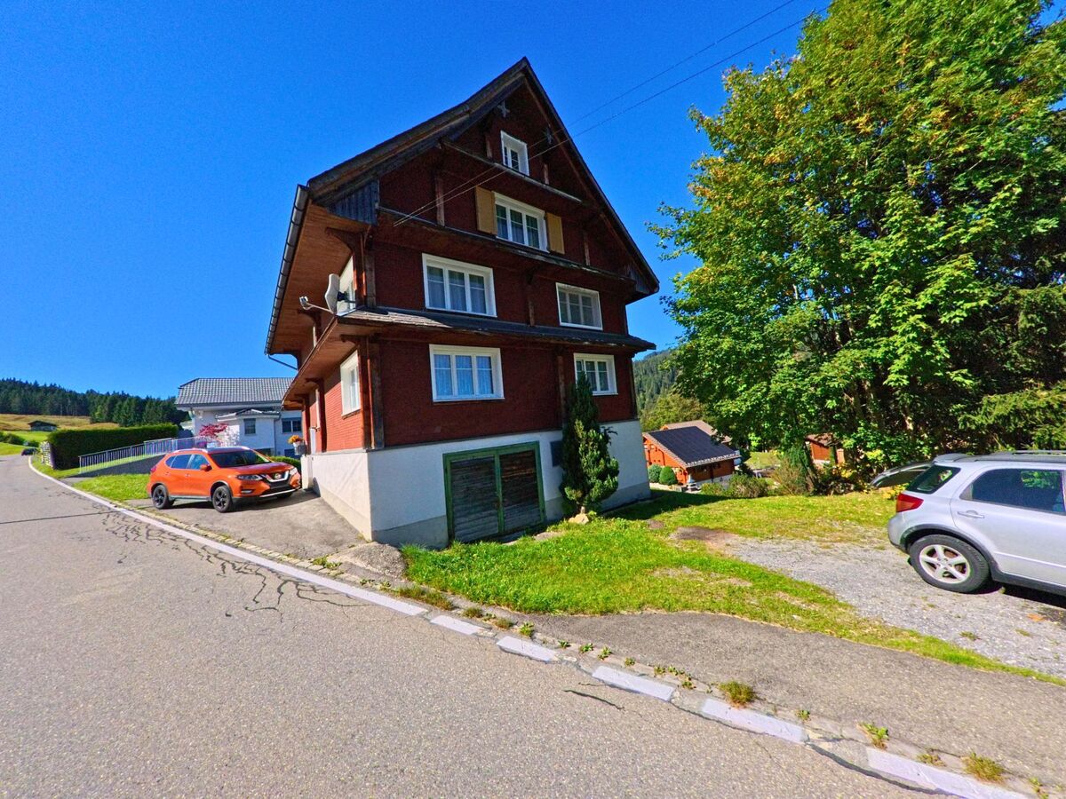 Ein Wohnhaus mit parkierendem Fahrzeug liegt an einer ruhigen Quartierstrasse in Oberiberg (8843, Kanton Schwyz).