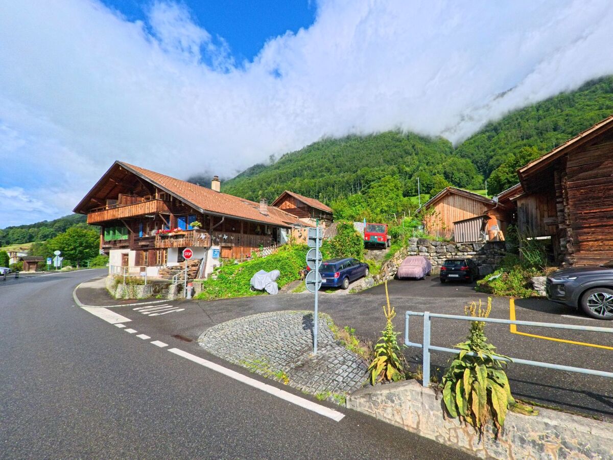 In Oberried am Brienzersee (3854, Kanton Bern) liegt ein rustikales Holzhaus an einer Kurve, umgeben von Nebelschwaden am bewaldeten Berghang.