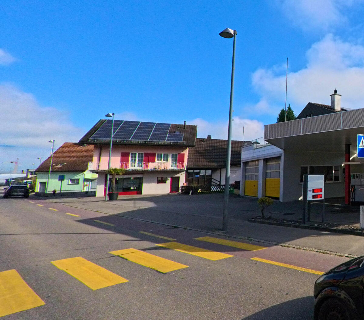 An einer Kreuzung mit Zebrastreifen liegen Geschaefts- und Wohnbauten in Oberriet (9463, Kanton St. Gallen).