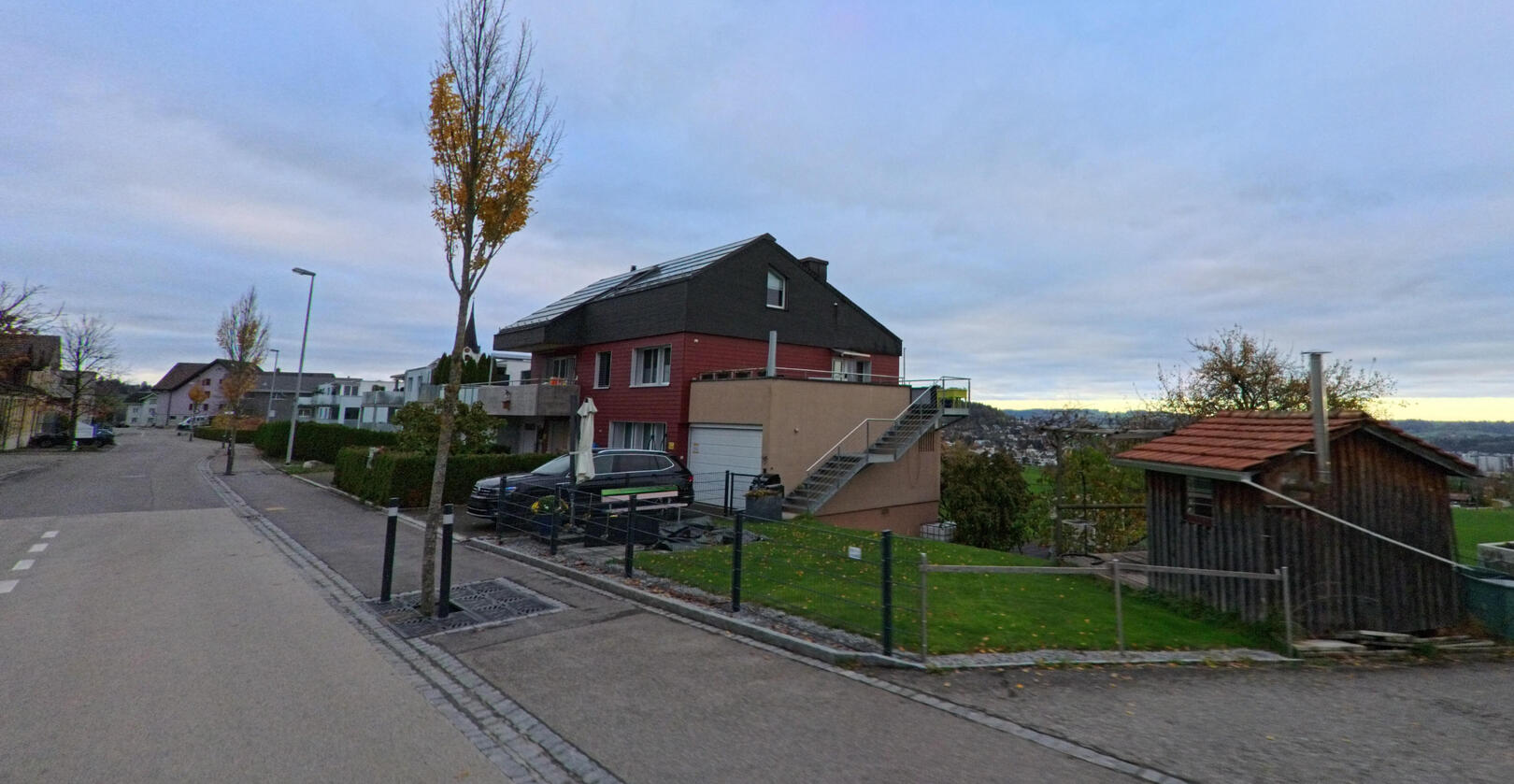 Entlang einer ruhigen Wohnstrasse in Oberuzwil (9248, Kanton St. Gallen) stehen moderne Einfamilienhaeuser mit Blick auf Gruenflaechen und das umliegende Siedlungsgebiet.