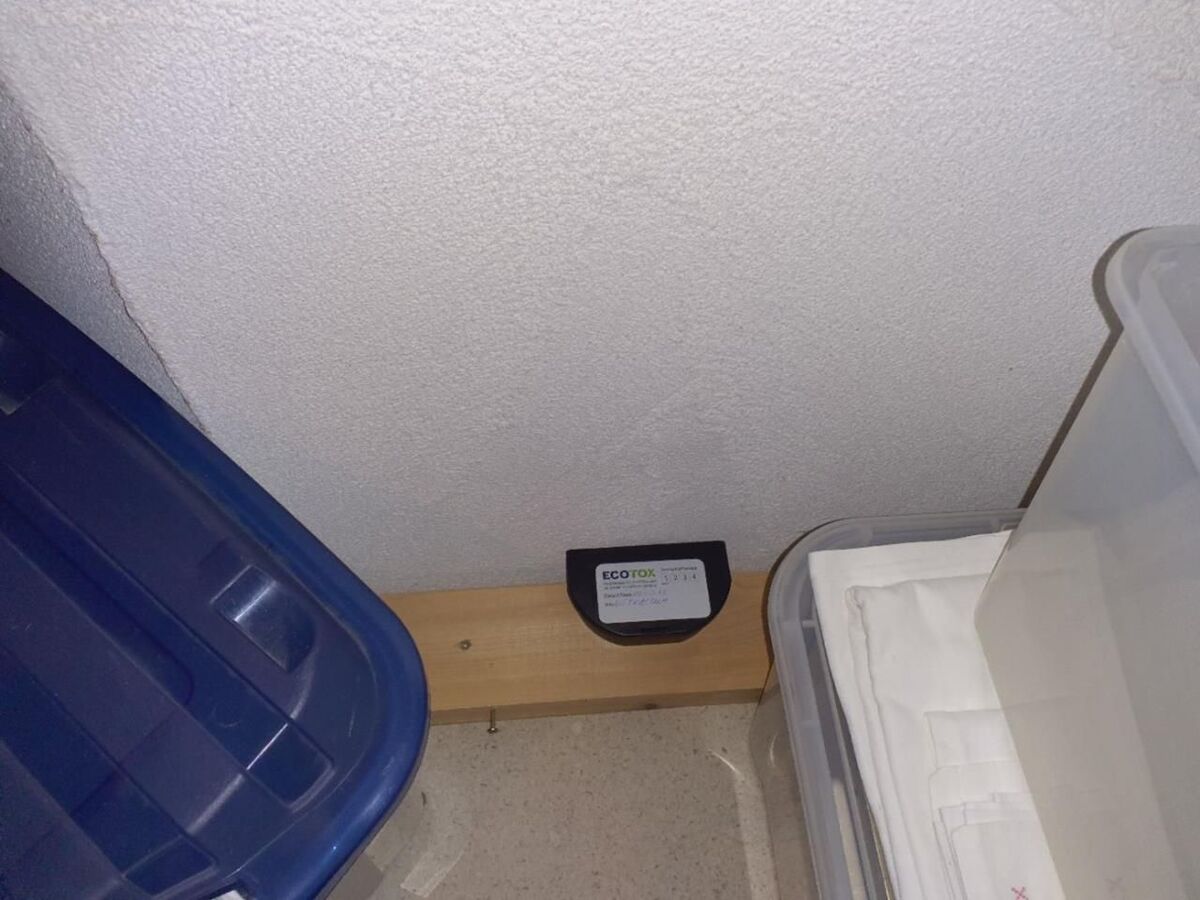 In einem Raum in Oberweningen (8165, Kanton Zürich) ist ein ECO-TOX-Gerät an der Wand zu sehen, neben einer blauen Aufbewahrungsbox und durchsichtigen Behältern, die sauber verstaut sind.