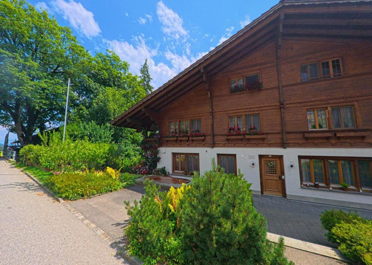 Ein traditionelles Wohnhaus mit reichem Blumenschmuck steht in Oberwil im Simmental (3765, Kanton Bern) direkt an einer ruhigen Strasse mit gepflegtem Vorgarten.