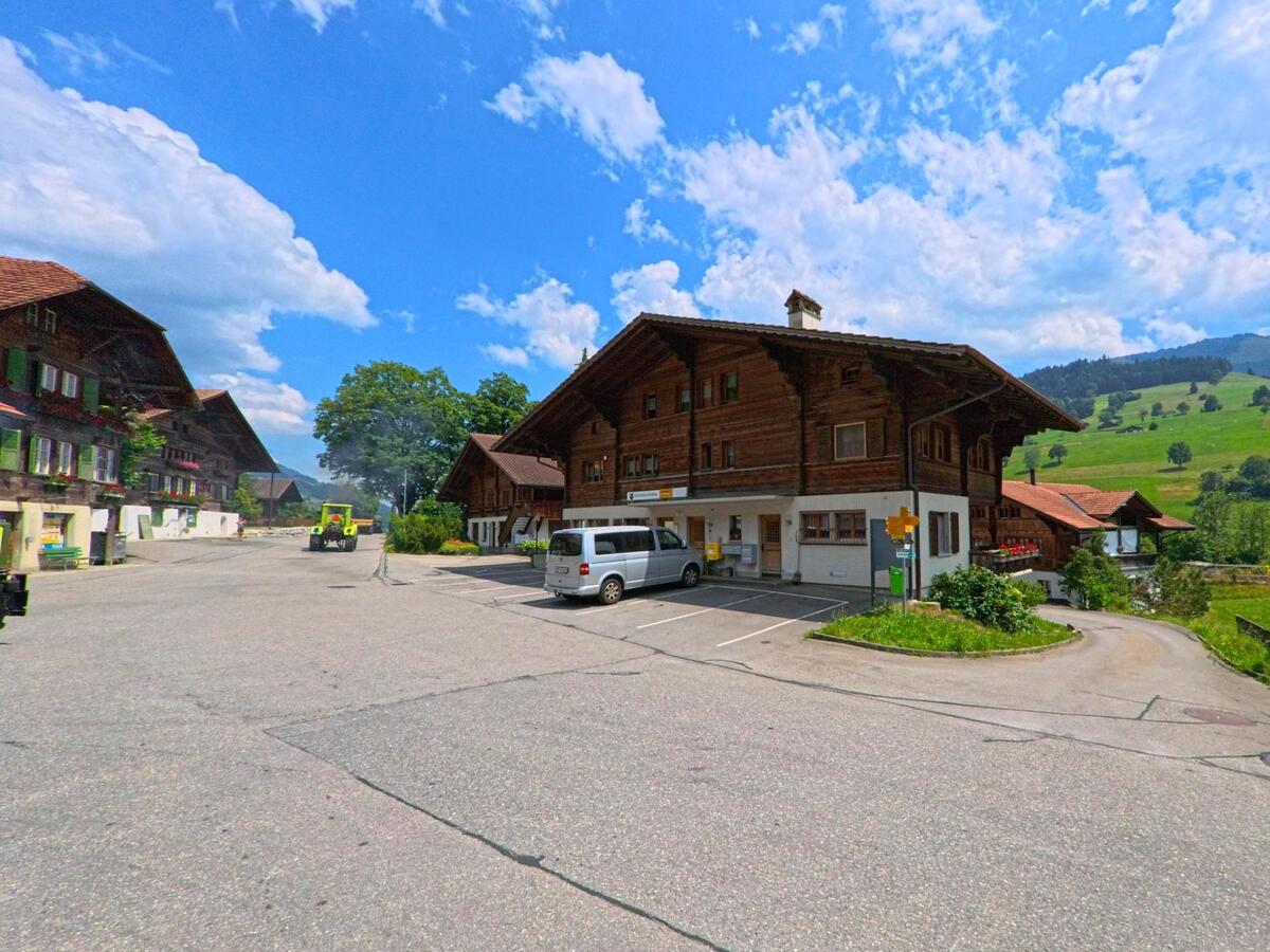 Im Zentrum von Oberwil im Simmental (3765, Kanton Bern) befindet sich ein Postgebäude im Erdgeschoss eines traditionellen Holzhauses mit angrenzendem Parkplatz.