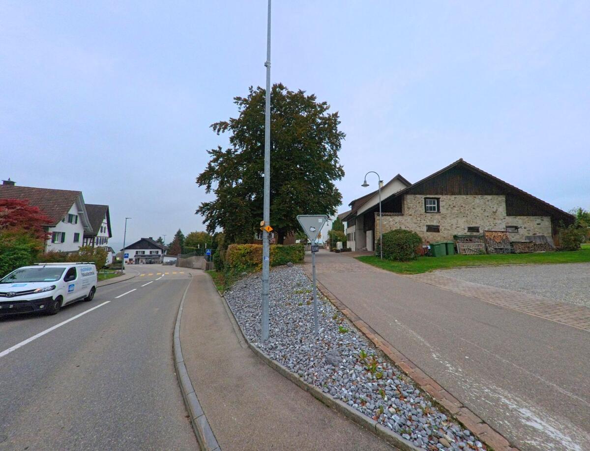 Ein Bauernhaus mit gemauerter Fassade und angrenzender Strasse prägt das Dorfbild von Oberwil-Lieli (8966, Kanton Aargau) an einem grauen Herbsttag.