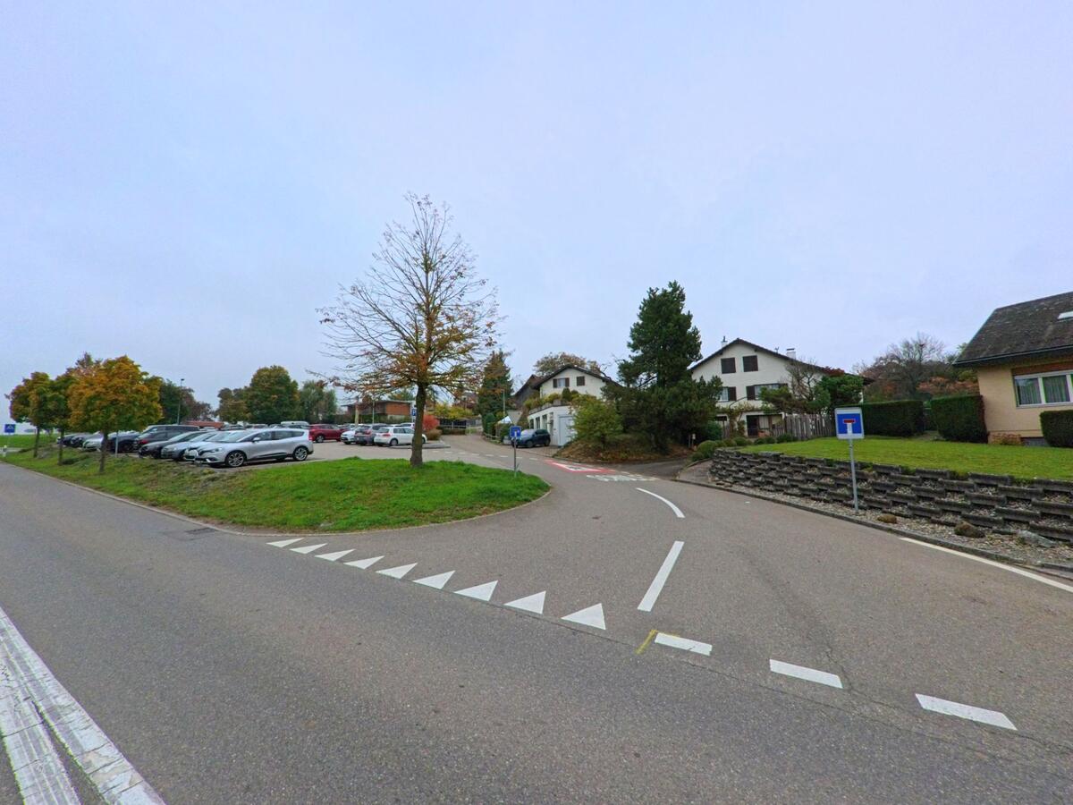 Ein Parkplatz mit mehreren Autos und angrenzenden Wohnhäusern liegt an einer Seitenstrasse in Oberwil-Lieli (8966, Kanton Aargau).
