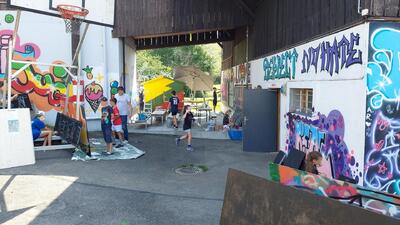 In Affoltern am Albis (8910, Kanton Zuerich) gestalten Kinder und Jugendliche in einem bunt besprayten Aussenbereich kreative Graffiti und nutzen den Raum fuer verschiedene Freizeitaktivitaeten.