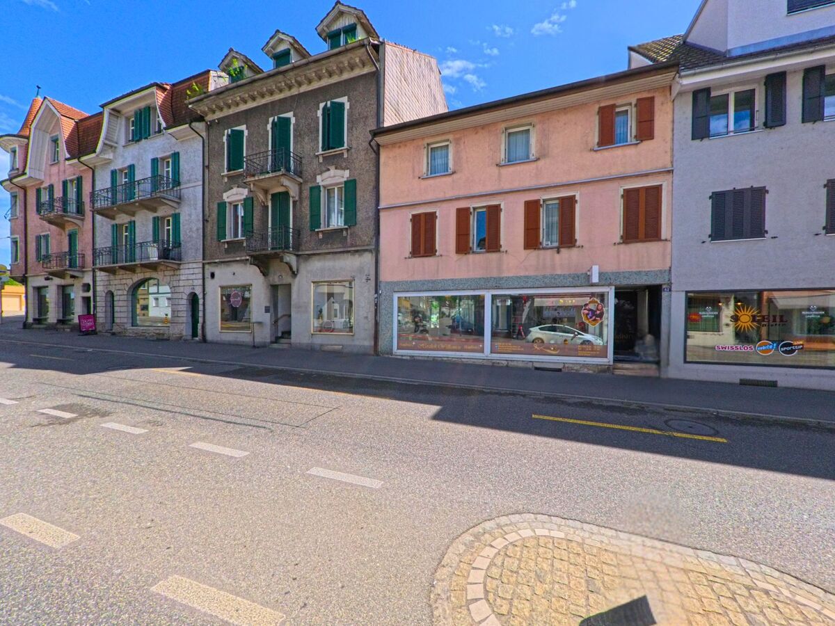 In Olten (4600, Kanton Solothurn) stehen entlang einer zentralen Strasse mehrgeschossige Altbauten mit Laeden im Erdgeschoss und Fensterlaeden in verschiedenen Farben.