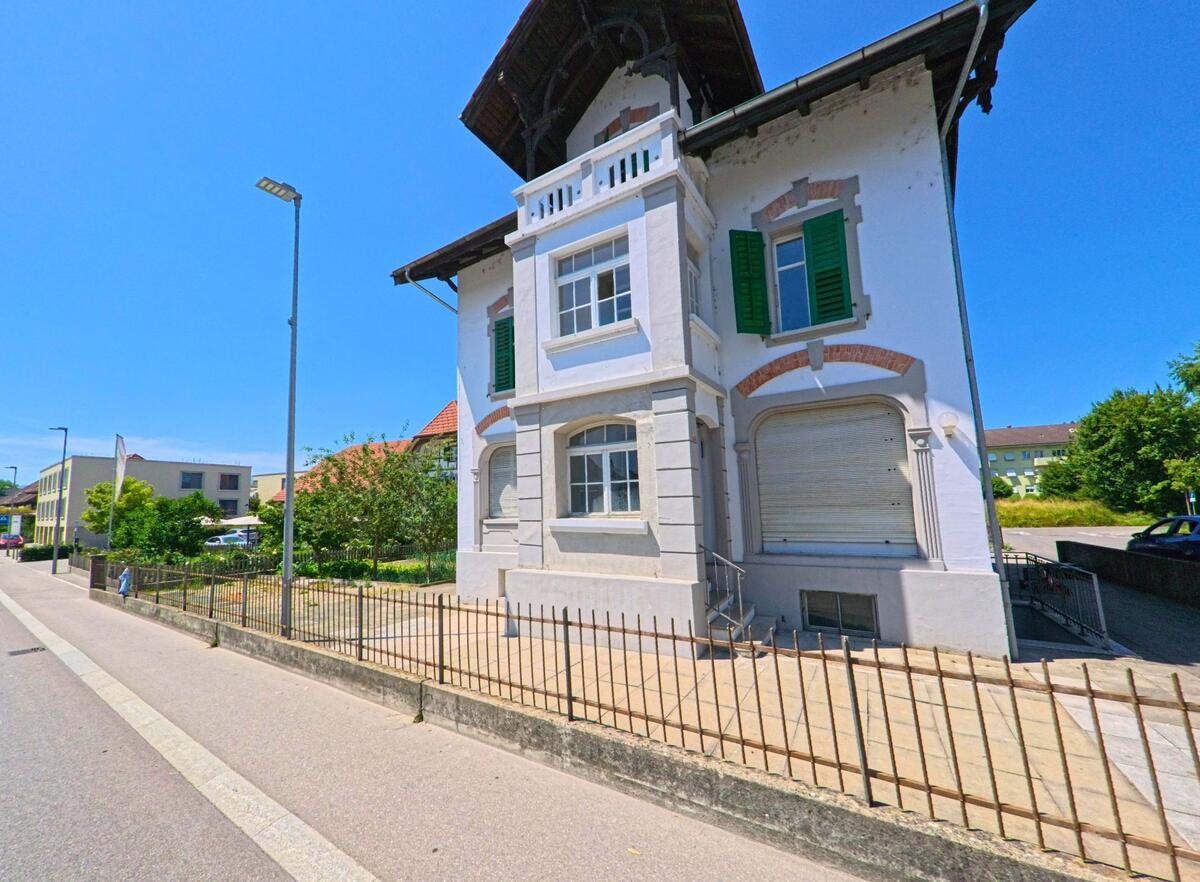 In Orpund (2552, Kanton Bern) steht ein historisches Wohnhaus mit grünen Fensterläden und reich verzierten Fassadenelementen direkt an einer Nebenstrasse.