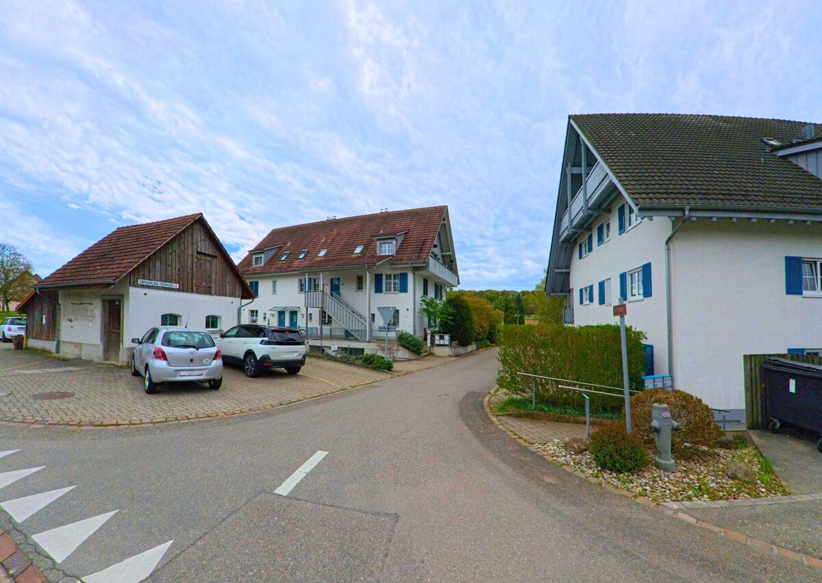 In Ossingen, PLZ 8475 im Kanton Zürich, münden mehrere ruhige Quartierstrassen in ein kleines Wohngebiet mit modernen Mehrfamilienhäusern und Parkplätzen.