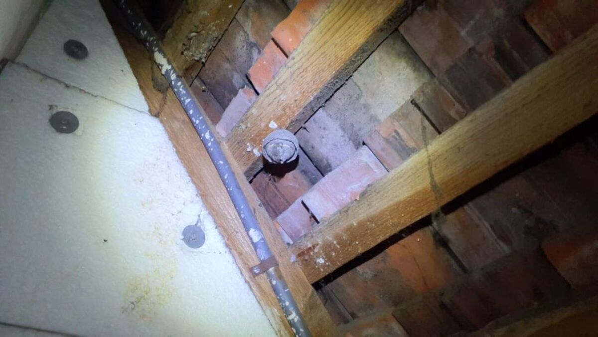  In einem Dachbodenbereich in Otelfingen (8112, Kanton Zürich) ist zwischen Ziegeln und Holzlatten ein altes Wespennest unter der Dachschräge erkennbar.