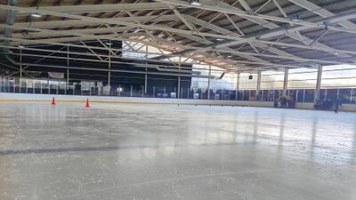 In der Patinoire de Romont in Romont (1680, Kanton Fribourg) trainiert eine Gruppe auf der hellen Eisflaeche einer ueberdachten Halle mit grossen Fenstern.