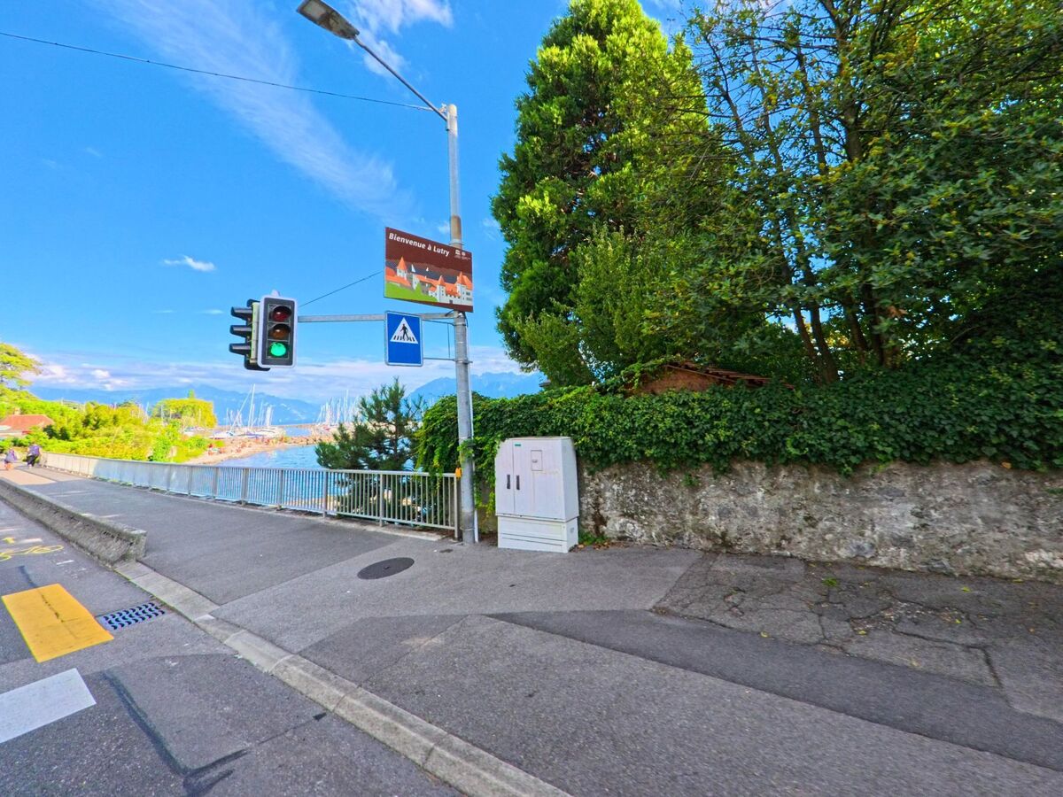 Am Seeufer in Paudex (1094, Kanton Waadt) fuehrt ein Gehweg mit Ampel und Blick auf zahlreiche Segelboote am Hafen entlang.