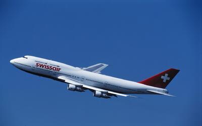 Ein Swissair-Flugzeug steigt in Kloten 8302 im Kanton Zurich vor blauem Himmel auf und zeigt deutlich die historische Swissair-Beschriftung.