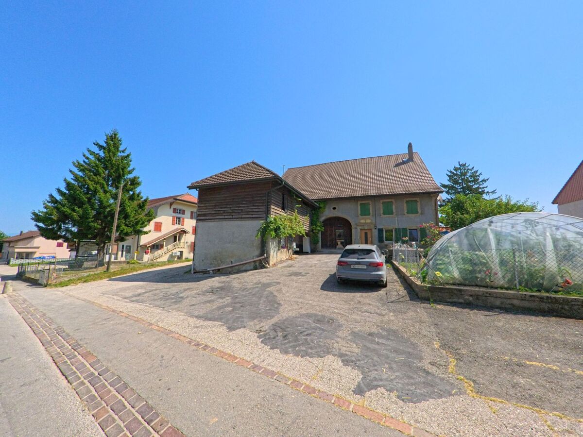 Ein traditionelles Bauernhaus mit Nebengebaeude und einem kleinen Gewaechshaus steht in Penthereaz (1375, Kanton Waadt).