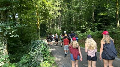 In einem waaldreichen Gebiet von Menzingen (6313, Kanton Zug) wandert eine Gruppe der Pfadi Menzingen gemeinsam einen schmalen Weg entlang.