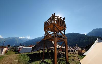 Ein selbstgebauter Holzturm steht in einem Zeltlager in Herisau (9100, Kanton Appenzell Ausserrhoden) waehrend Personen oben darauf stehen und in die Ferne schauen.